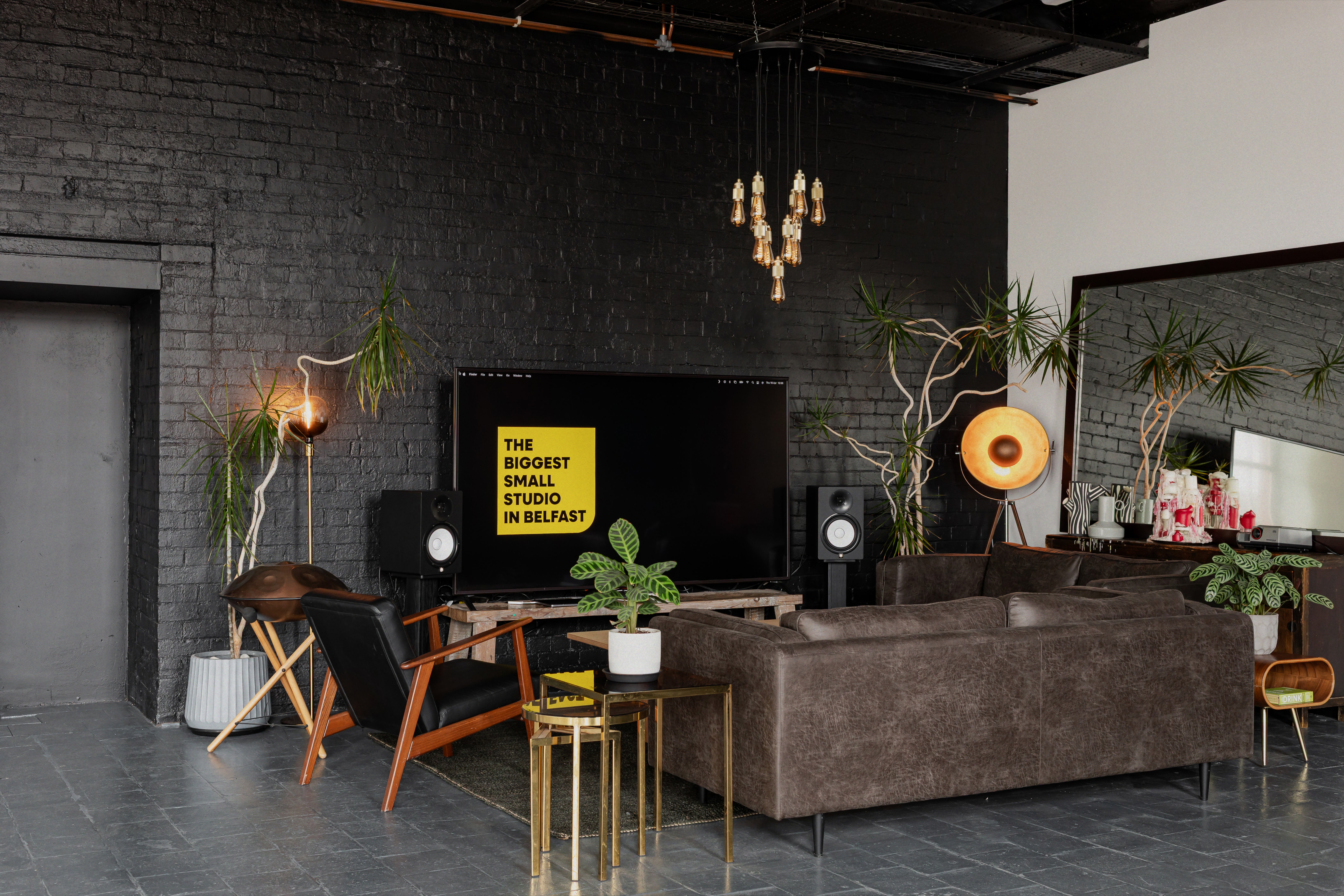 Industrial lounge area with leather sofas, black brick walls and large TV at Basedot Studio.