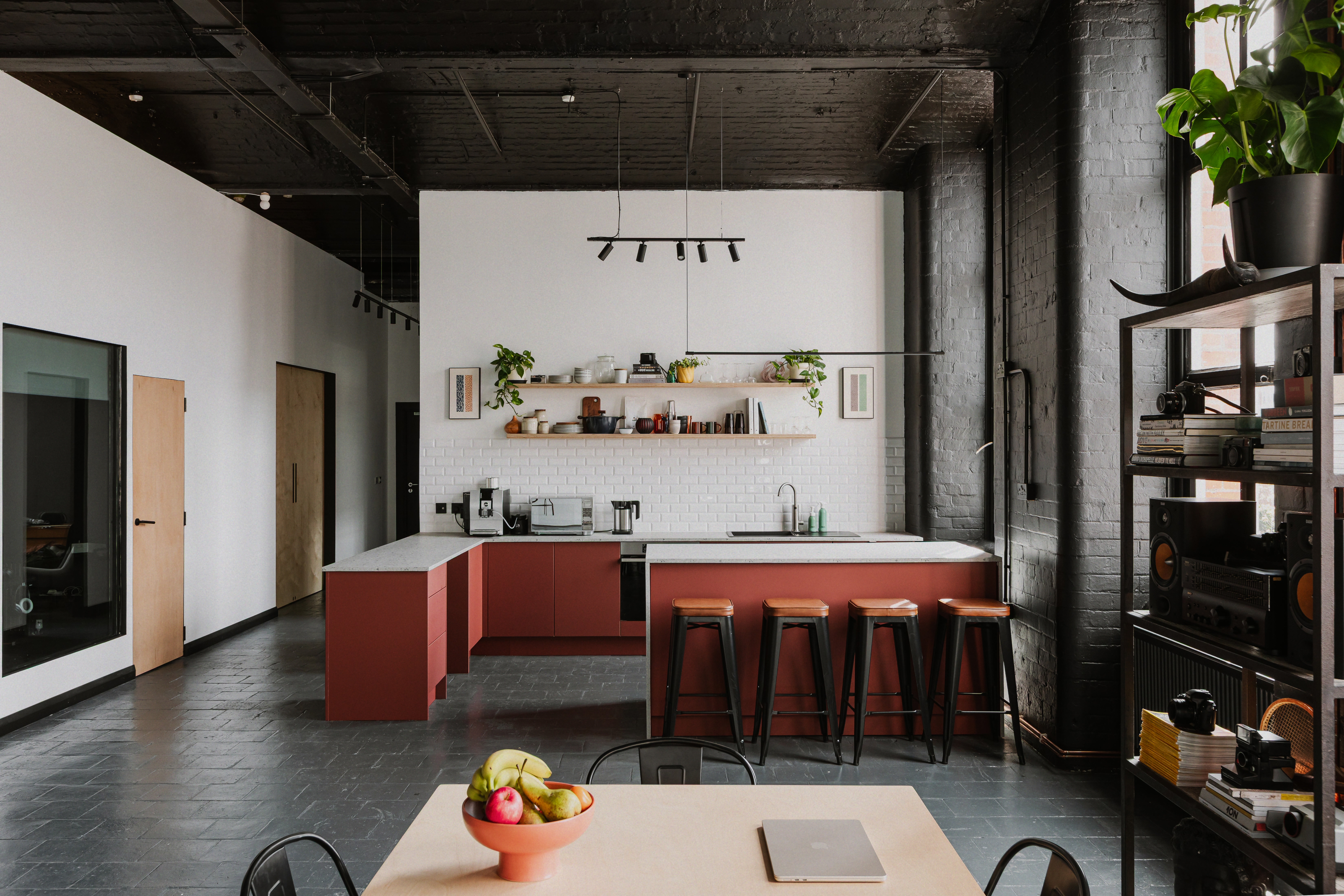 Open-plan studio kitchen with dining table and industrial black brick interior.