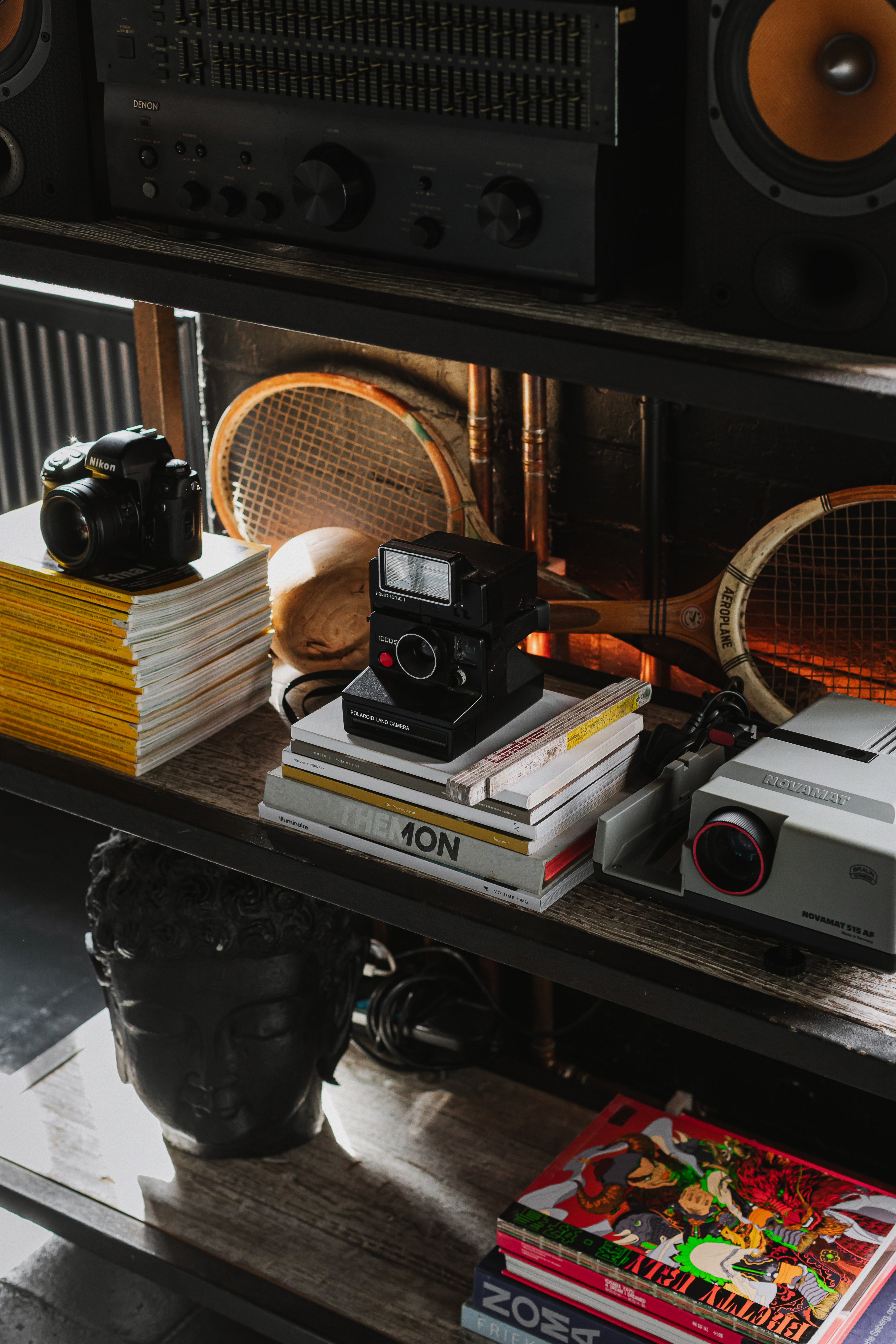 Vintage cameras, projector, magazines and audio equipment on industrial shelving.