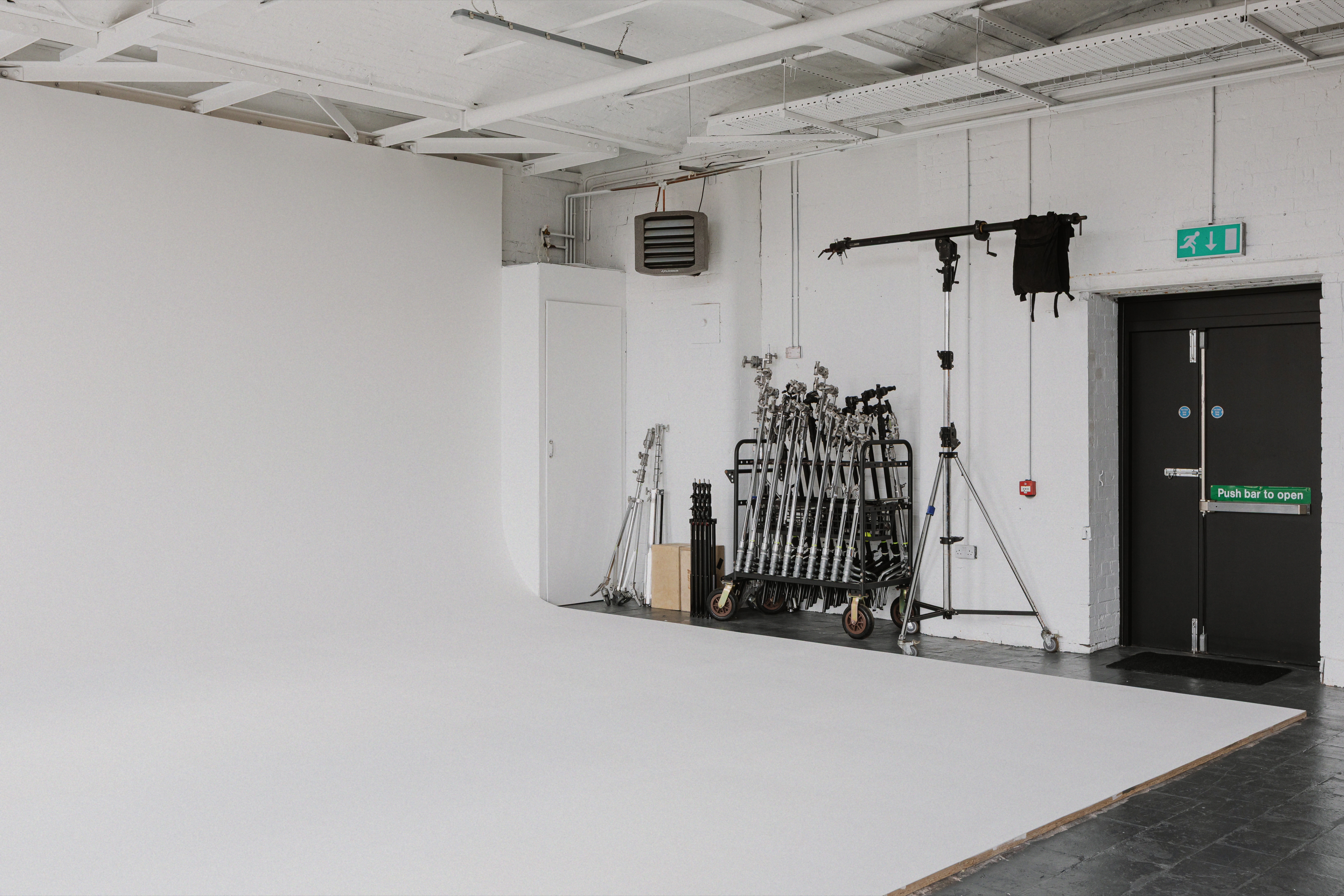 Side view of white cyclorama with organised lighting stands and grip equipment.