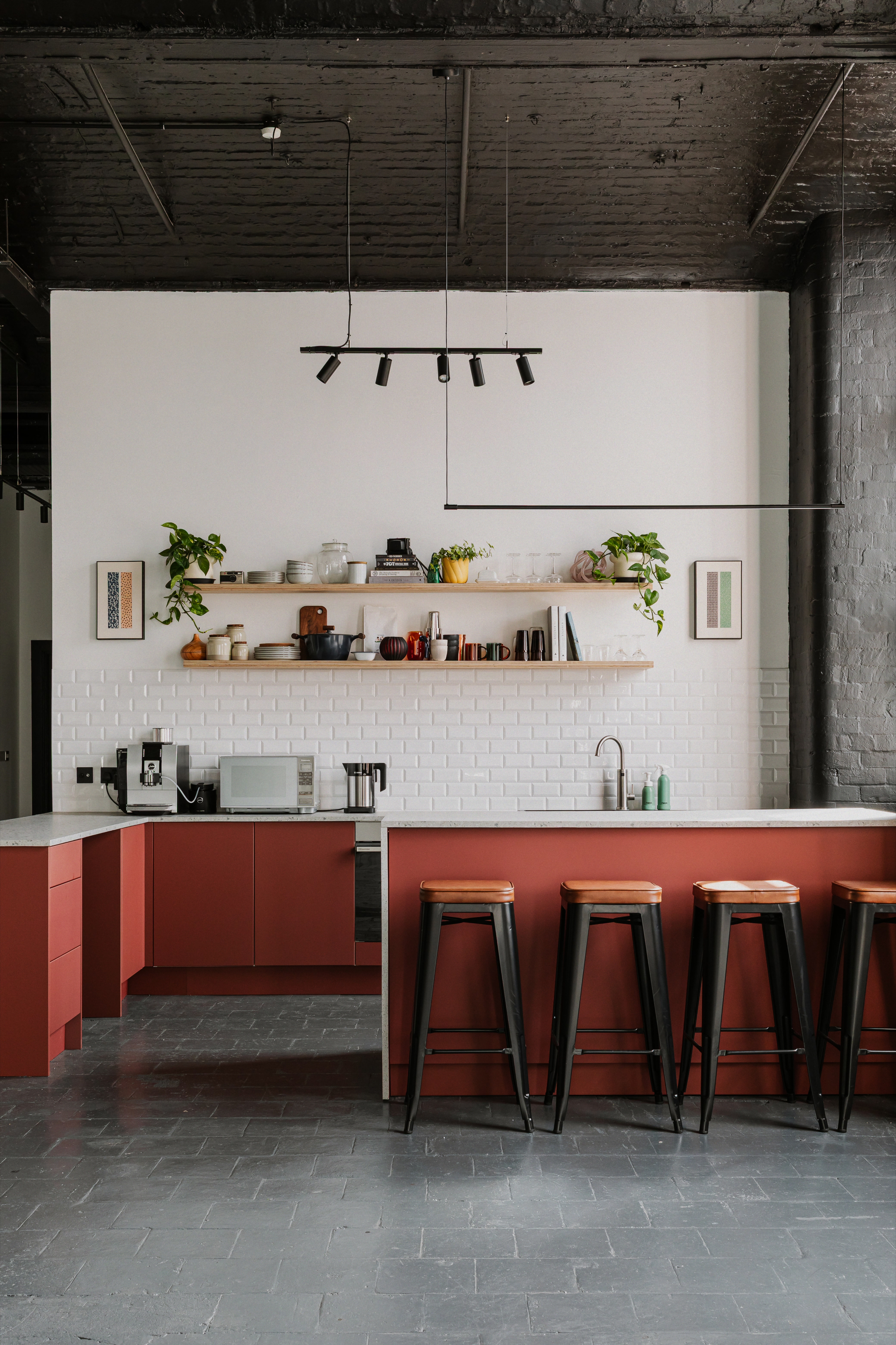 Red fitted kitchen with breakfast bar and stools in industrial Belfast studio.