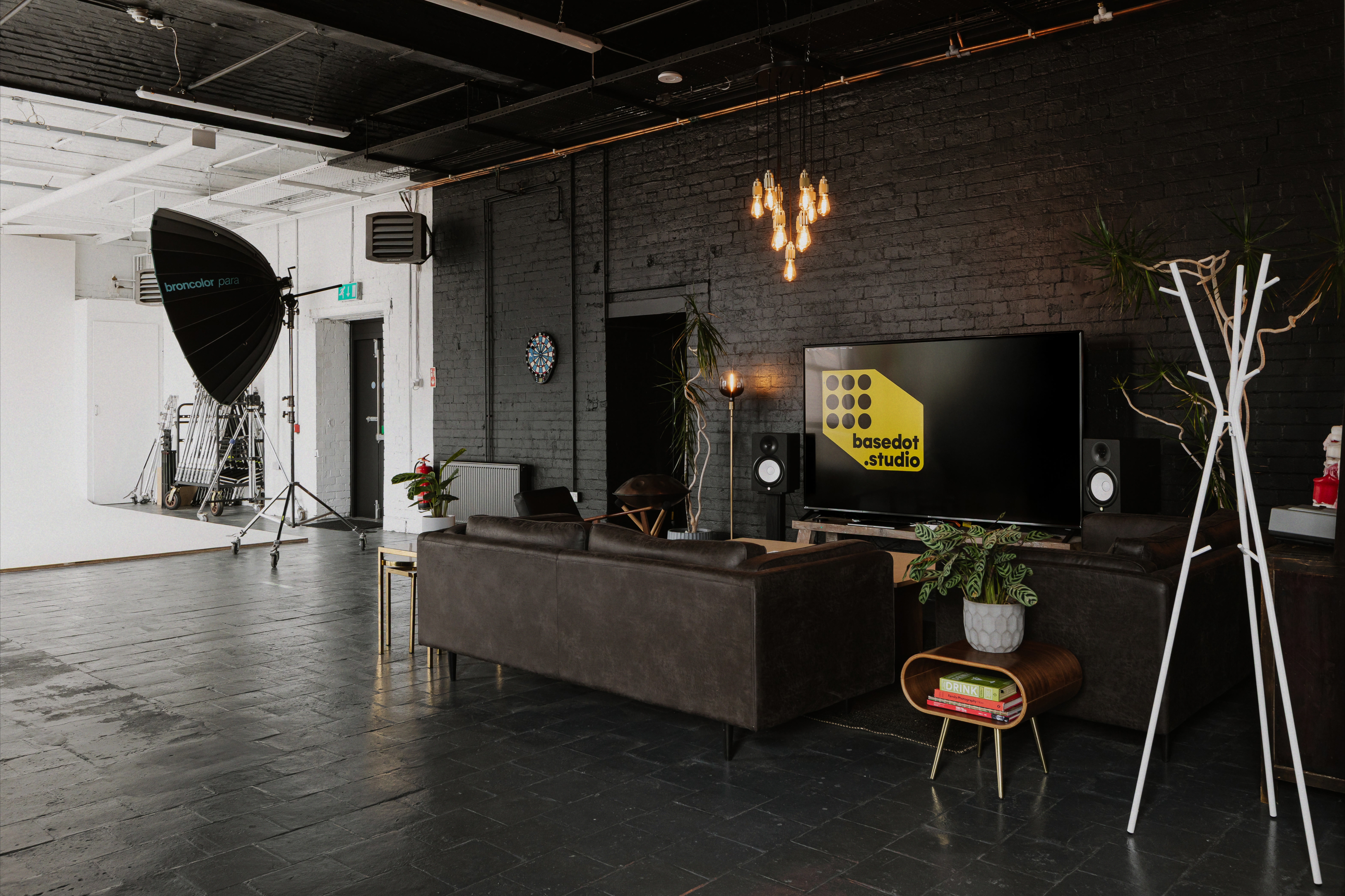 Leather lounge area beside white cyclorama in large industrial photo studio.
