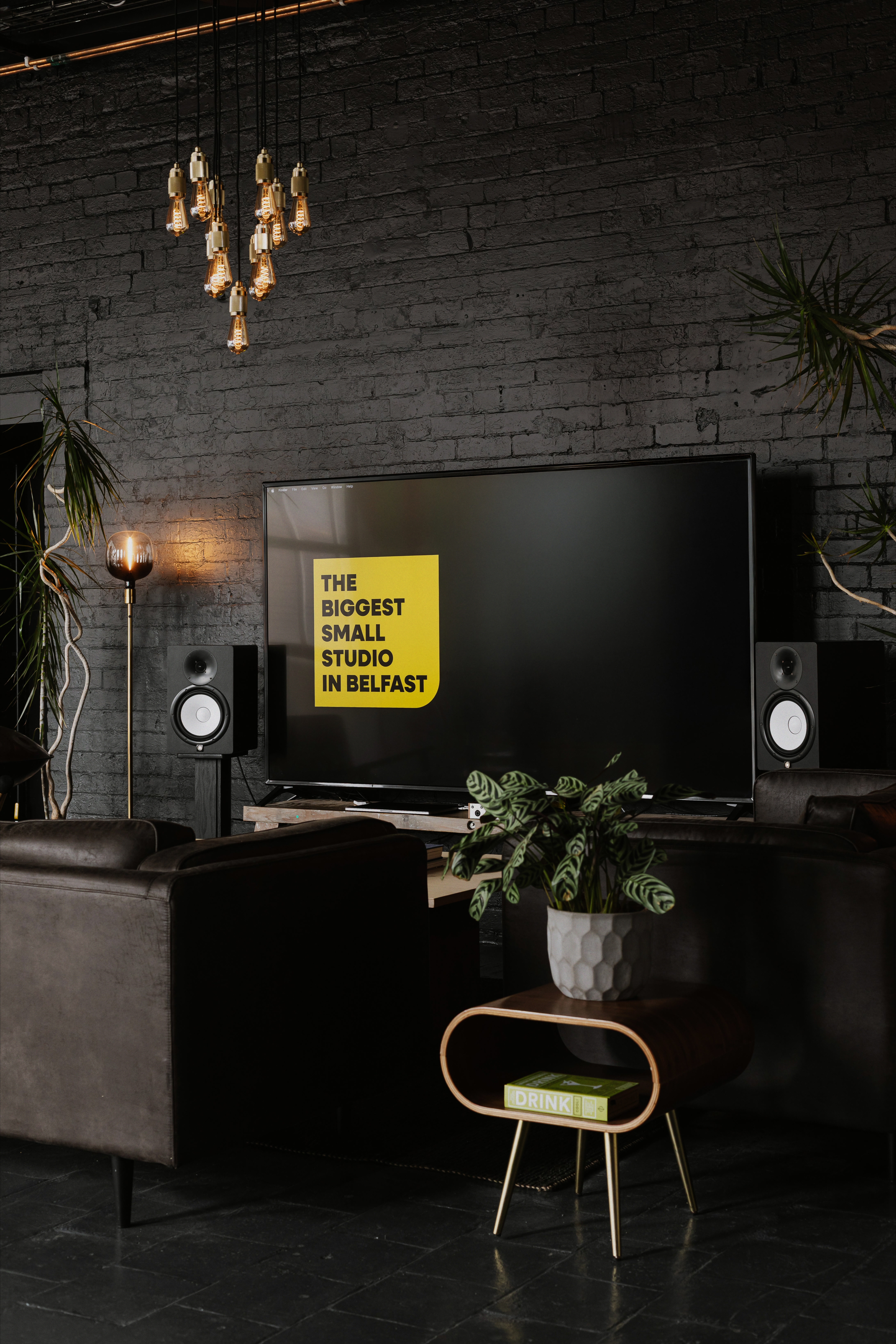 Dark lounge with leather seating, plants and Basedot Studio display screen.